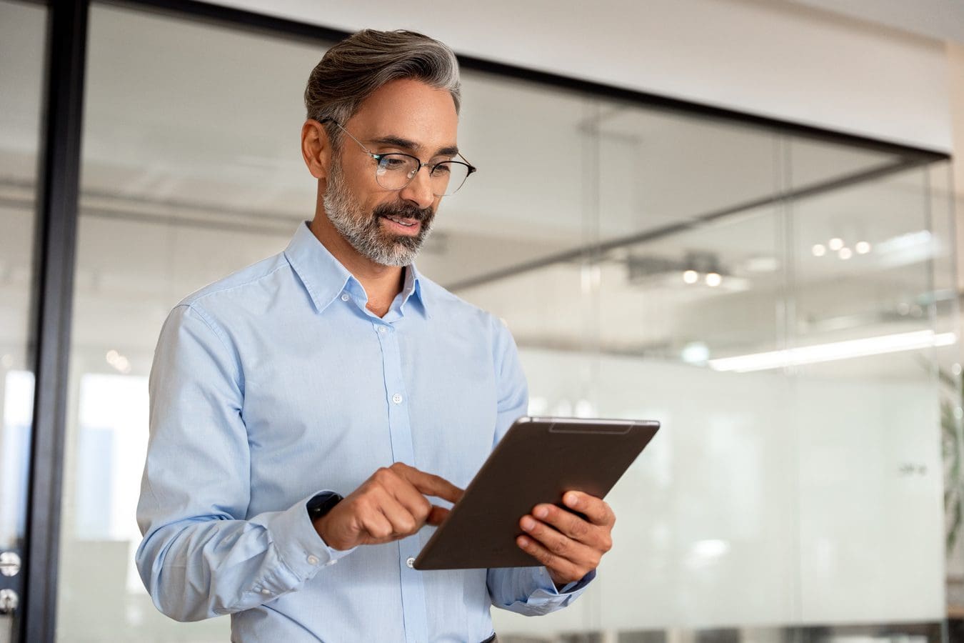 A man in glasses is holding an ipad