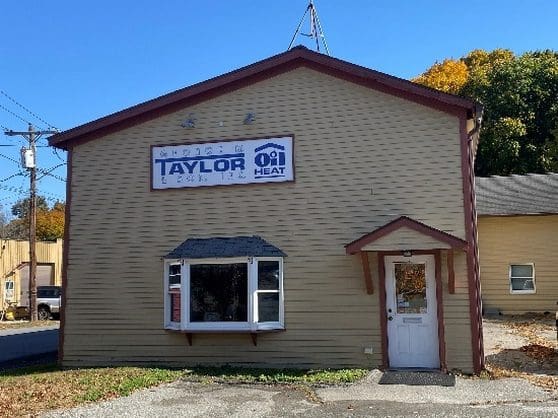 A tan building with a white door and blue sign.