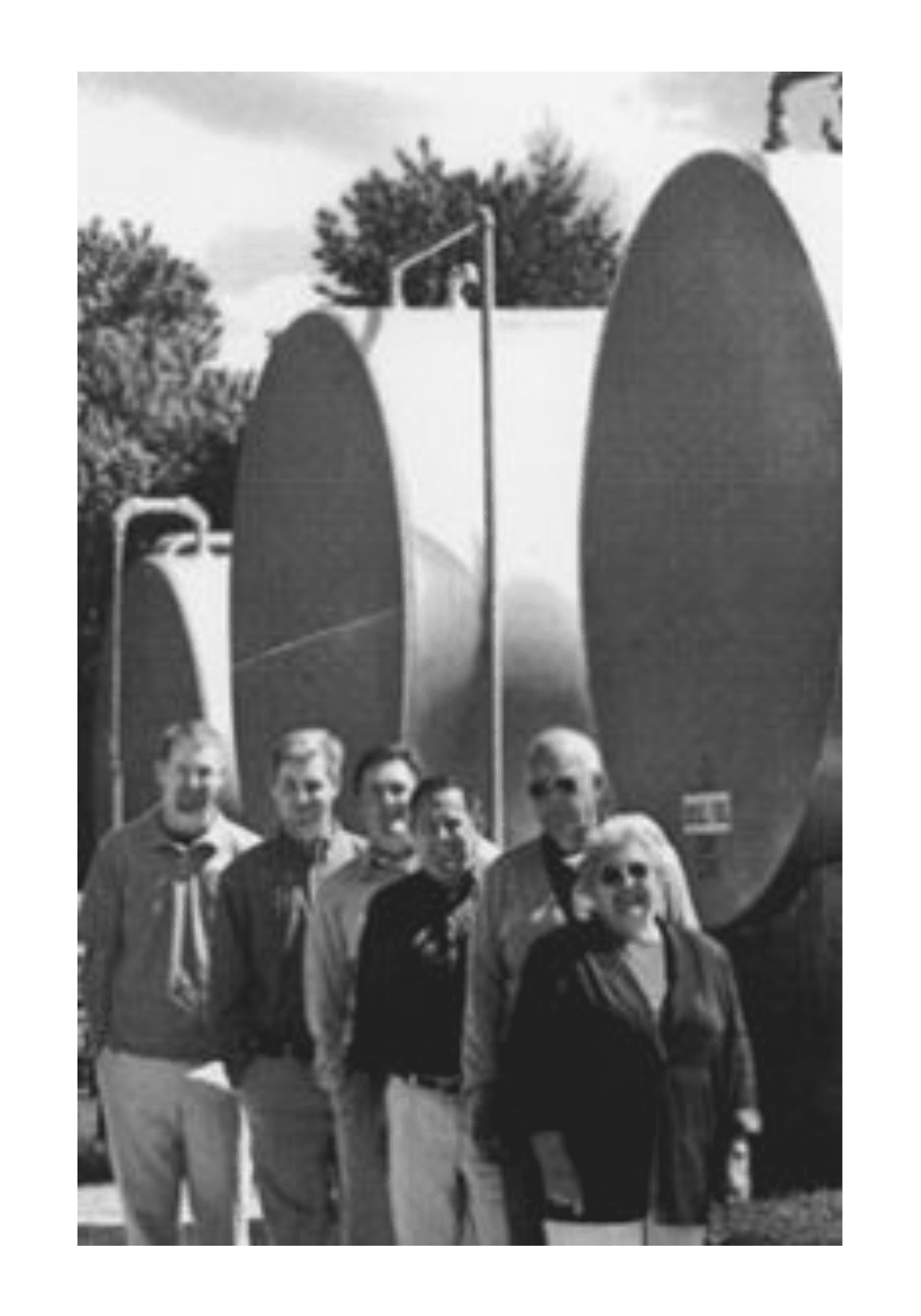 A group of people standing in front of large tanks.