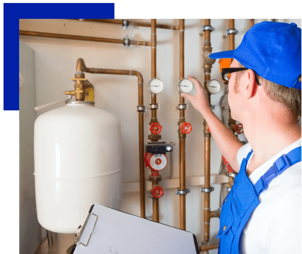 A man in blue shirt and hat next to pipes.